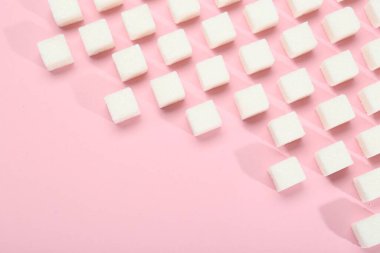 Pembe arka planda beyaz şeker küpleri, üst manzara. Metin için boşluk