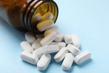 Açık mavi arka planda şişe ve vitamin kapsülleri, yakın plan