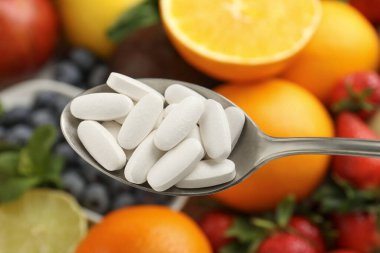 Kaşık içinde vitamin hapları taze meyvelerin üstünde, yakın plan.