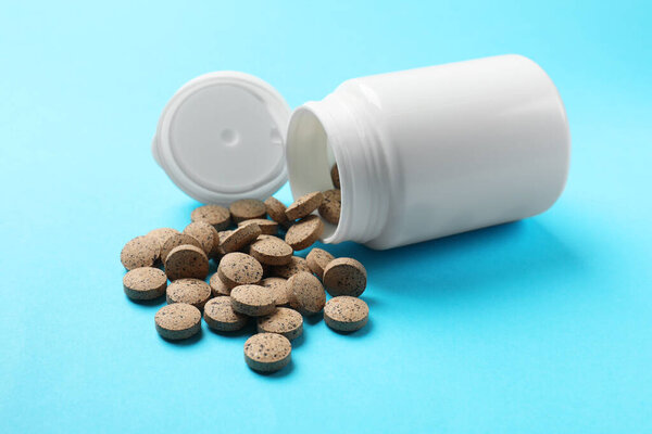 Bottle and vitamin pills on light blue background