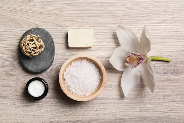Düz kompozisyon, spa ürünleri ve açık ahşap masa üzerinde güzel bir çiçek.