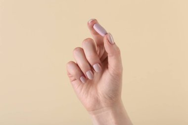 Bej arka planda vitamin hapı tutan kadın, yakın plan. Sağlık takviyesi