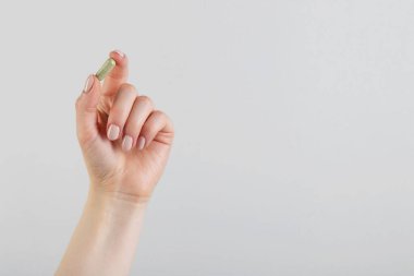 Gri arka planda vitamin kapsülü tutan kadın, metin için yeri olan yakın plan. Sağlık takviyesi