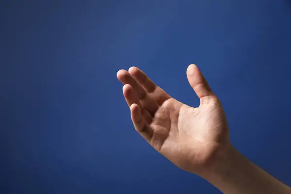 Man Håller Något Handen Blå Bakgrund Närbild — Stockfoto