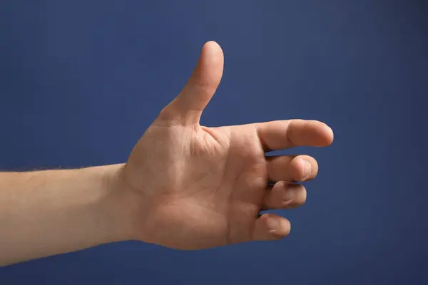 Man Håller Något Handen Blå Bakgrund Närbild — Stockfoto