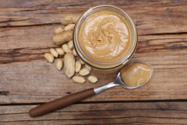 Kavanozda fıstık ezmesi ve tahta masada kaşık.