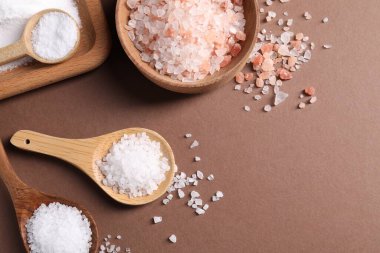 Kahverengi arka planda farklı bulaşık takımlarındaki doğal tuz, düz. Metin için boşluk