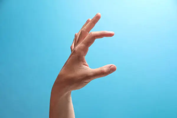 Man Håller Något Handen Ljusblå Bakgrund Närbild — Stockfoto