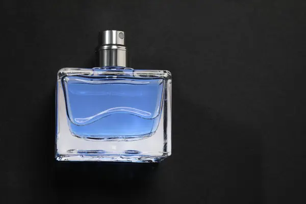 Blue men\'s perfume in bottle on black background, top view. Space for text