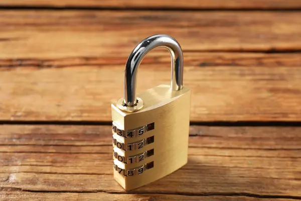 One steel combination padlock on wooden table, closeup