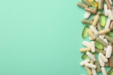 Turkuaz arka planda farklı vitamin kapsülleri, üst görünüm. Metin için boşluk