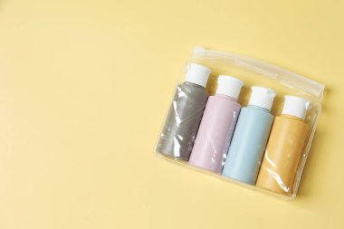 Sarı arka planda plastik çantada kozmetik seyahat seti, üst manzara. Metin için boşluk
