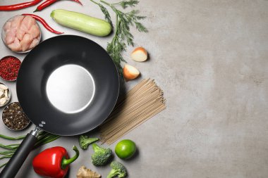 Gri masadaki ham malzemelerle çevrili boş demir tava, düz. Metin için boşluk