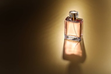 Lüks kadın parfümü. Altın arka planda güneş ışığı şişesi, metin için boşluk