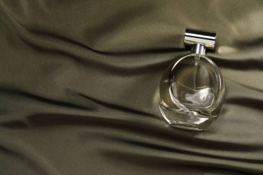 Parfüm şişede koyu ipek kumaş, üst görünüm.