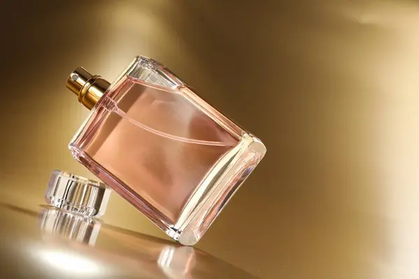 Luxury women\'s perfume. Sunlit glass bottle on golden background, space for text