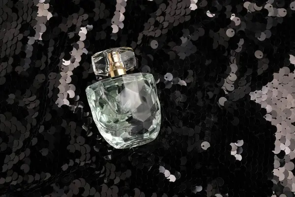 色彩艳丽的香水装在装有亮晶晶亮片的面料上的瓶子里 上图所示 — 图库照片