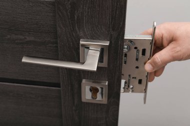 Tamirci kapı kolunu içeride değiştiriyor, yakın çekim görüntüsü var.