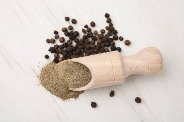 Aromatik baharat. Kepçe içinde yer biberi ve beyaz ahşap masada siyah biber.