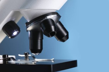 Açık mavi arkaplanda bir mikroskop, yakın plan