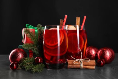 Lezzetli Sangria kadehleri ve Noel süslemeleri koyu dokulu masada, yakın plan.