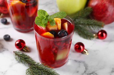 Aromatik Sangria içeceği bardaklarda, malzemelerde ve beyaz mermer masada Noel dekorunda.