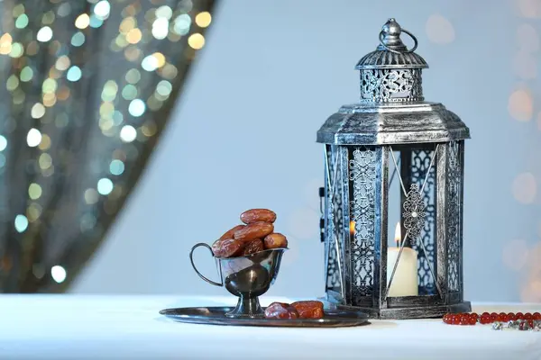 stock image Arabic lantern, misbaha and dates on table against blurred lights, space for text