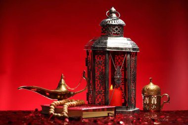 Arapça fener, Kuran, Misbaha ve Aladdin sihirli lamba parlak kırmızı masada.