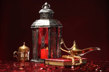 Arapça fener, Kuran, Misbaha ve Aladdin sihirli lamba parlak kırmızı masada.
