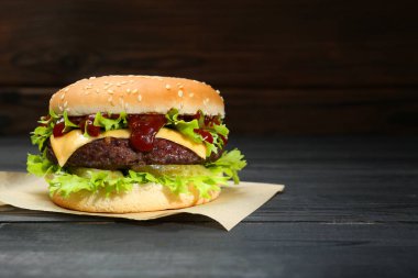 Siyah ahşap masada leziz köfteli burger, metin için yer.