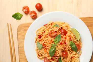 Vejetaryen yemeği. Taze domatesli lezzetli makarna ve ahşap masada fesleğen.