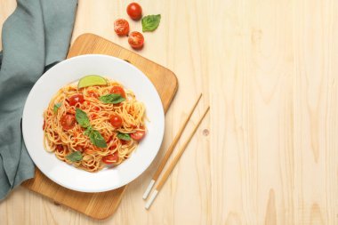 Vejetaryen yemeği. Taze domatesli lezzetli makarna ve ahşap masada fesleğen. Metin için boşluk