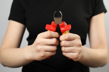 Gri arka planda çapraz pense olan kadın, yakın plan.