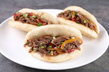 Gri masadaki tabakta leziz gua bao, yakın plan.