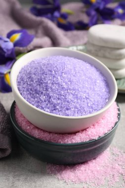 Gri masadaki farklı deniz tuzu ve spa taşları, yakın plan.