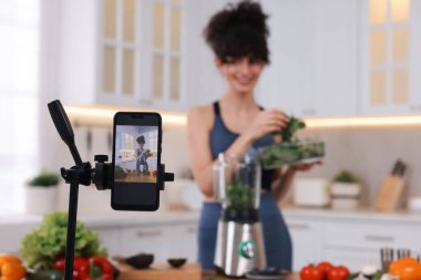 Mutfakta video kaydederken yemek blogcusu yemek pişiriyor, akıllı telefona odaklan