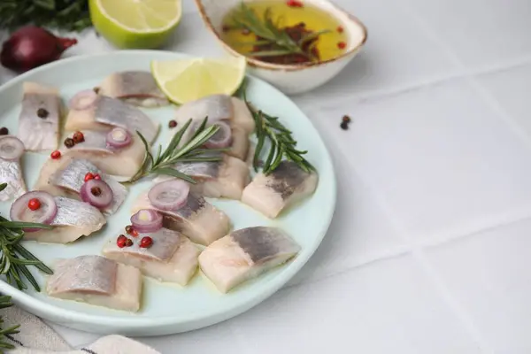 Tasty marinated fish with rosemary and spices on light tiled table, closeup. Space for text