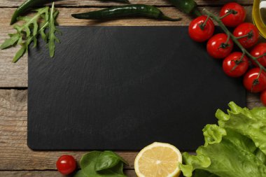 Yemek pişiriyorum. Siyah kesme tahtası ve ahşap masa üzerinde farklı ürünler, düz yatıyordu.