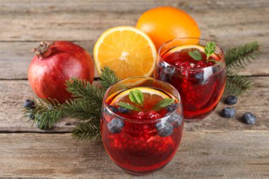 Aromatik Noel Sangria kadehleri, köknar dalları ve ahşap masa malzemeleri.
