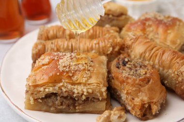 Doğu tatlıları. Lezzetli baklava parçalarının üzerine bal dök, yakın plan.