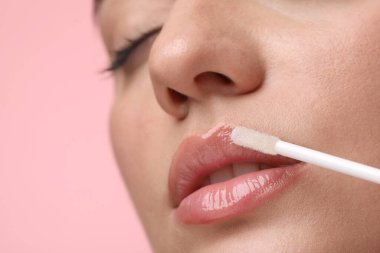Pembe arka plana dudak parlatıcısı sürmüş bir kadın, yakın plan. Metin için boşluk