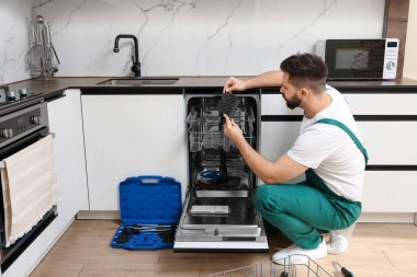 Mutfaktaki bulaşık makinesini inceleyen servis elemanı.