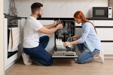 Güzel bir çift bulaşık makinesini tabakla dolduruyor.