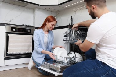 Güzel bir çift bulaşık makinesini tabakla dolduruyor.