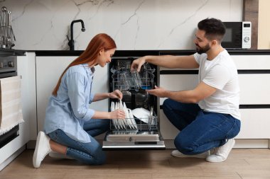 Güzel bir çift bulaşık makinesini tabakla dolduruyor.
