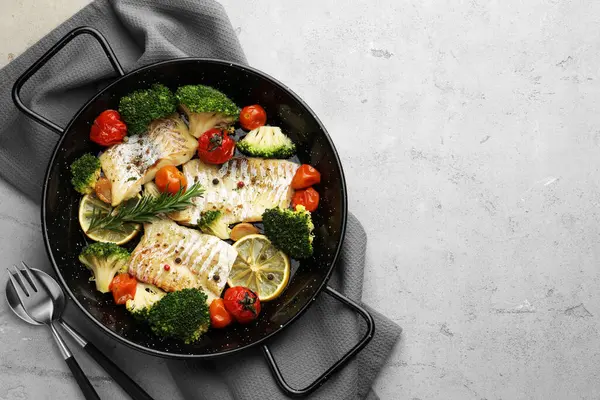 Tasty cod cooked with vegetables served on grey table, flat lay. Space for text