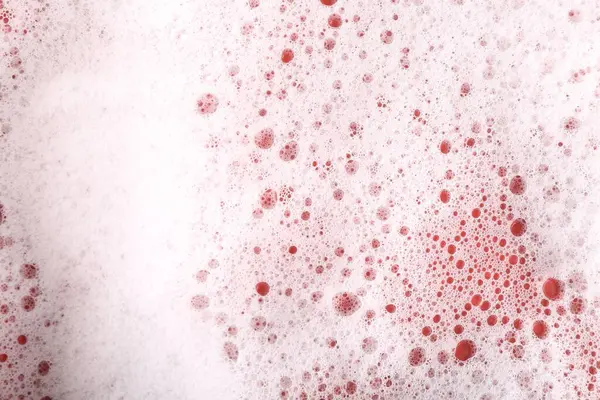 White foam with bubbles on red background, above view
