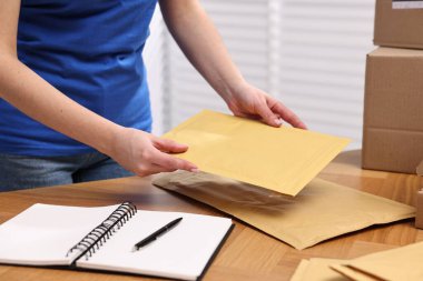 Postane çalışanı ahşap masaya paket topluyor. Kapalı bir masa.