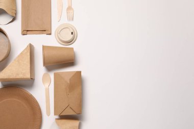 Çevre dostu gıda ambalajı. Kağıt kaplar, beyaz arka planda çanta ve sofra takımı, düz yatak. Metin için boşluk