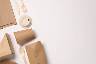 Çevre dostu gıda ambalajı. Kağıt kaplar, beyaz arka planda çanta ve sofra takımı, düz yatak. Metin için boşluk